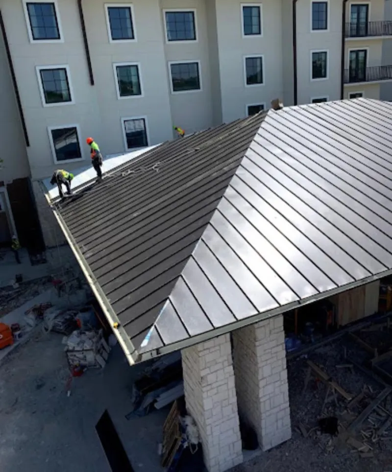 Crew installing standing seam metal roof panels on a commercial project in Soledad